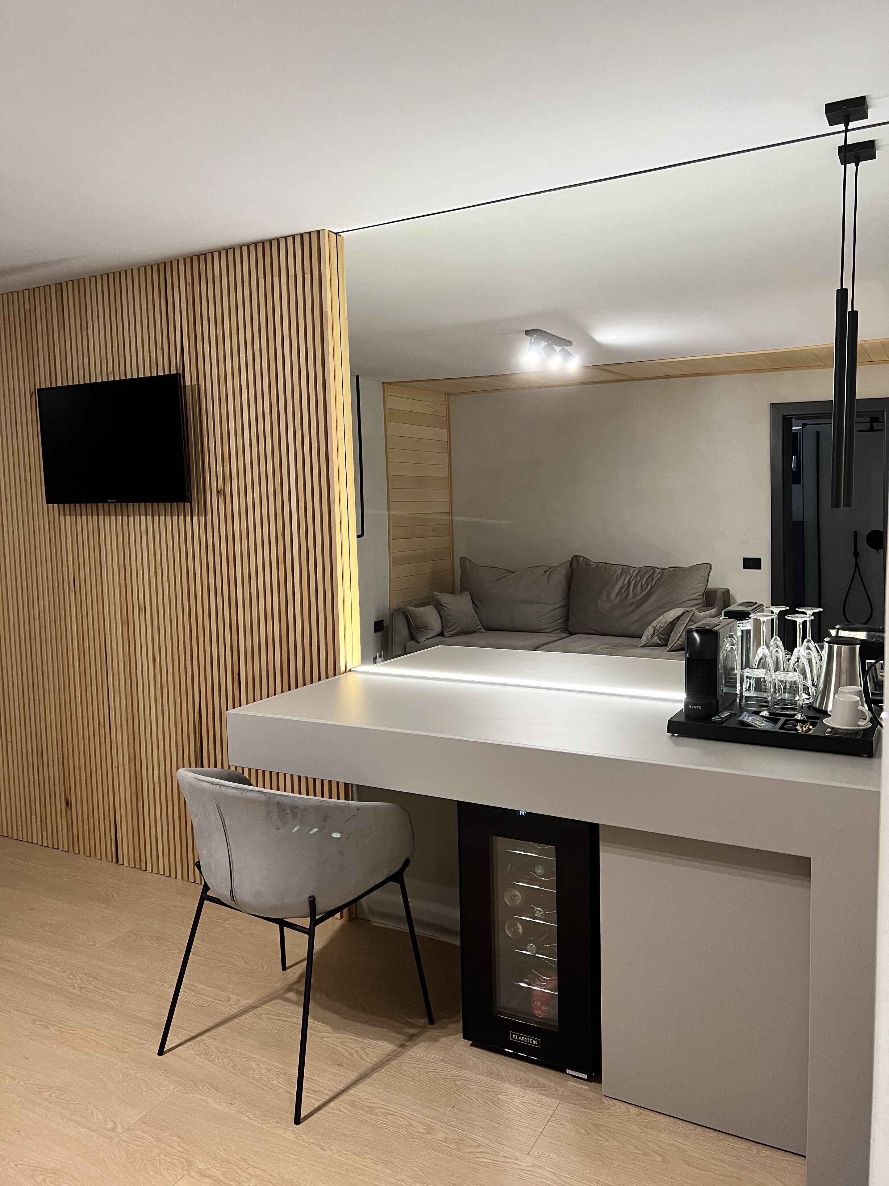Una cocina moderna con una isla integrada, un televisor de pantalla plana montado en una pared de madera y una cafetera sobre la isla.