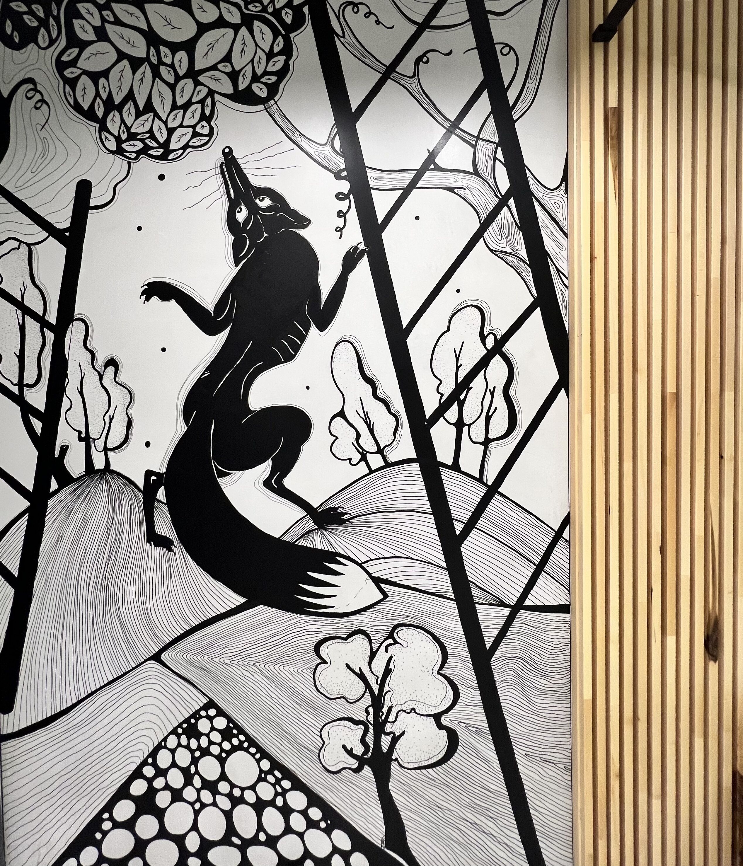 A black and white mural with abstract shapes and a figure.