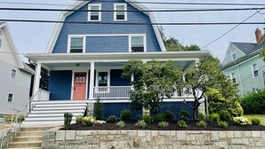 A two-story house with a blue exterior, white trim, and a red front door. - Beautifully Remodeled Family Size Apartment, Ideal for Downtown & Beach Getaway (Westerly)