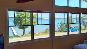 Ein Zimmer mit großen Fenstern und Blick auf einen See sowie einen Steg.