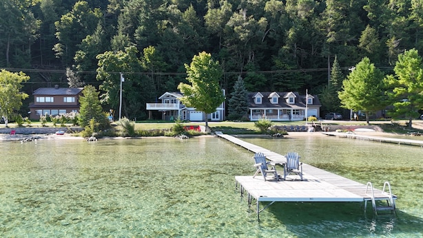 Ein Haus am Seeufer mit Steg, klarem Wasser und einer Veranda.