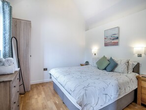A bedroom with a bed, bedside tables, a mirror, and a painting on the wall. - 2 bedroom accommodation in Chepstow (Chepstow)