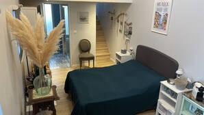 Ein Schlafzimmer mit Bett, Nachttisch, Stuhl und Blick auf eine Treppe, die zu einem Schlafboden führt.