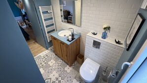 Ein modernes Badezimmer mit einem weißen Waschbecken, einem Spiegel und einer Toilette.