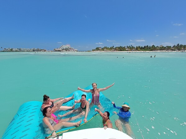 A group of people on a blue inflatable raft in clear turquoise water. - Together to Cancún  (Cancun)