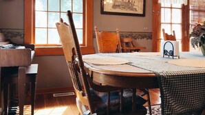 Un comedor con una mesa de madera, sillas, un reloj y un cuadro en la pared.