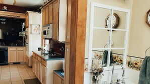 Una cocina con armarios de madera, microondas y lavamanos con un jarrón de flores.