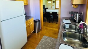 A compact kitchen with wooden cabinets, a white refrigerator, a stainless steel sink, and a ceiling fan. - Countryside Escape - 10 minutes from downtown South Haven! (Bangor)