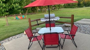 An outdoor patio with a grill, red chairs, and a red umbrella. - Countryside Escape - 10 minutes from downtown South Haven! (Bangor)