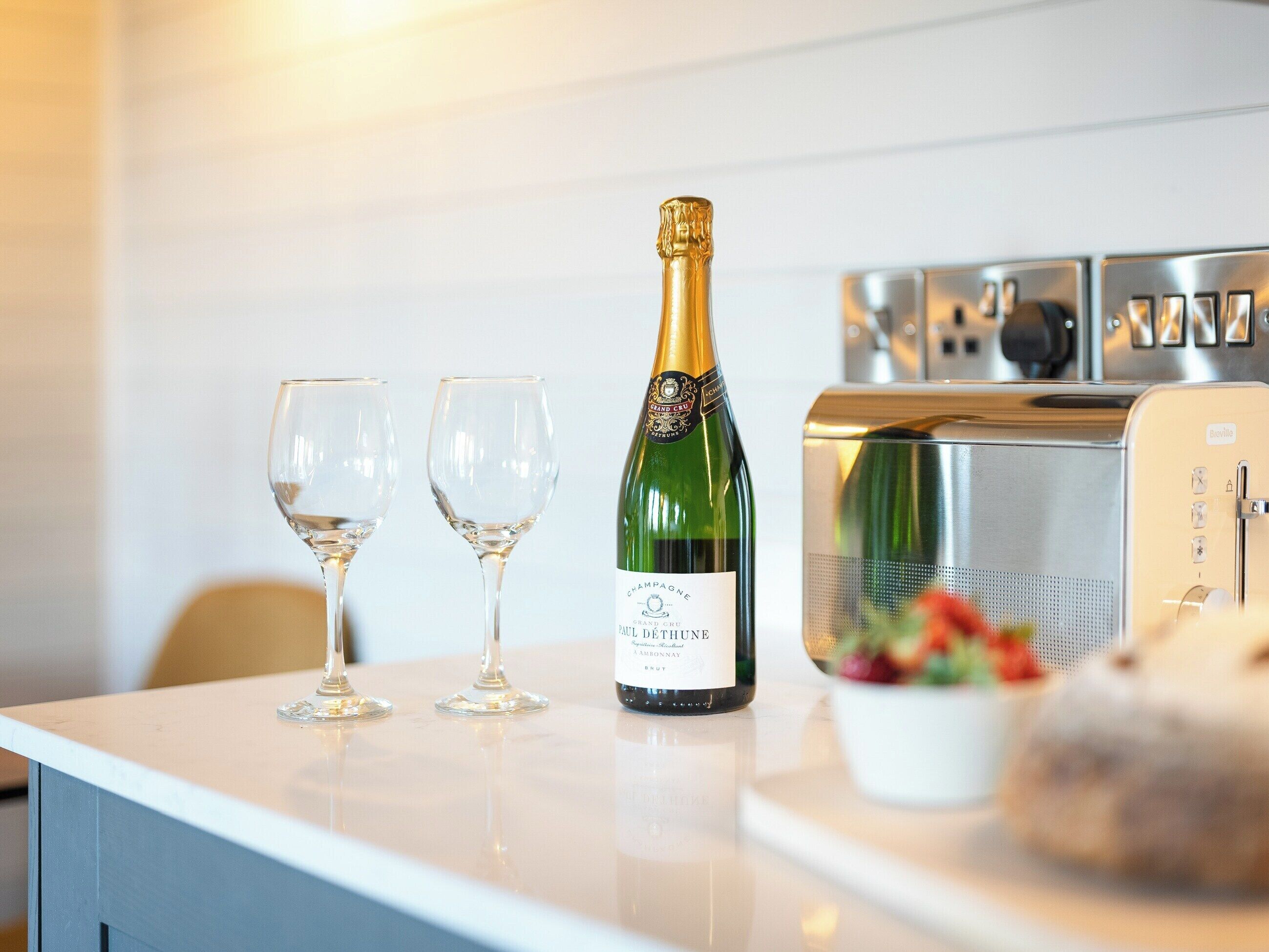 En champagneflaske og to glas på en bordplade.