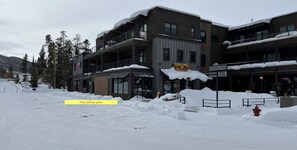 A multi-story building with balconies, a sign indicating 'Free parking spots', and a snow-covered ground.