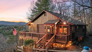 A log cabin with a wooden deck and stairs, surrounded by trees and mountains. - Mountain view cabin near Ellijay w/ hot tub! (Gilmer County)