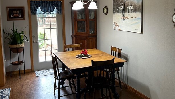 Una sala da pranzo con tavolo in legno, sedie, un lampadario, una credenza e un quadro appeso al muro.