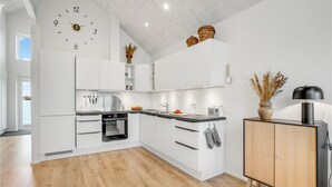 A modern kitchen with white cabinetry, a built-in oven, a sink, and a wooden cabinet with a lamp. - Amazing apartment in Ringkøbing (Ringkøbing)