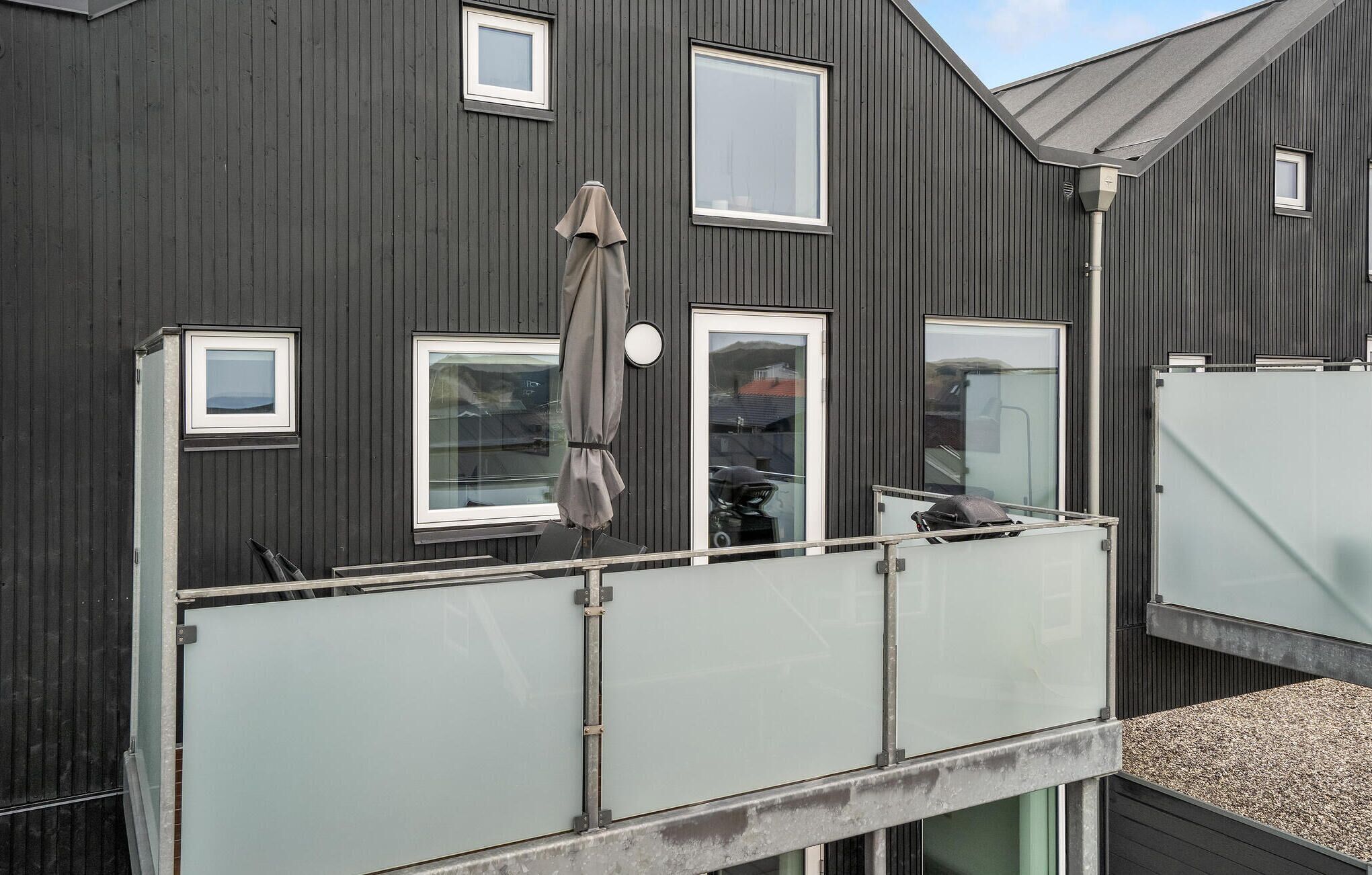Ein modernes Gebäude mit zahlreichen Fenstern und einem Balkon mit Metallgeländer.