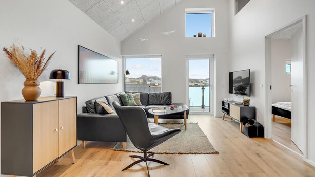 A modern living room with a sofa, a coffee table, a TV, and a view of the sea. - Amazing apartment in Ringkøbing (Ringkøbing)