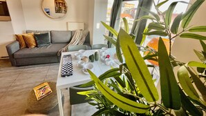 Una sala de estar moderna con un sofá gris, una mesa de centro blanca y un amplio ventanal con cortinas.