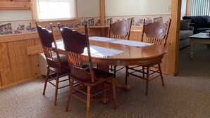 A dining area with a wooden table and chairs, a patterned wall, and a view of a living room. - SPRING GETAWAY! Comfortable 2BR cozy cottage just a few steps from Sandusky Bay! (Sandusky)