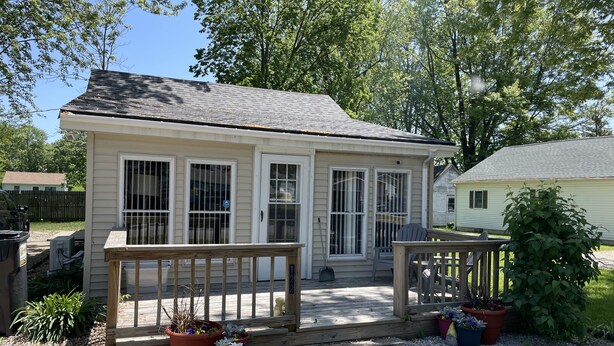 A small, single-story house with a front porch, a deck, and potted plants. - SPRING GETAWAY! Comfortable 2BR cozy cottage just a few steps from Sandusky Bay! (Sandusky)