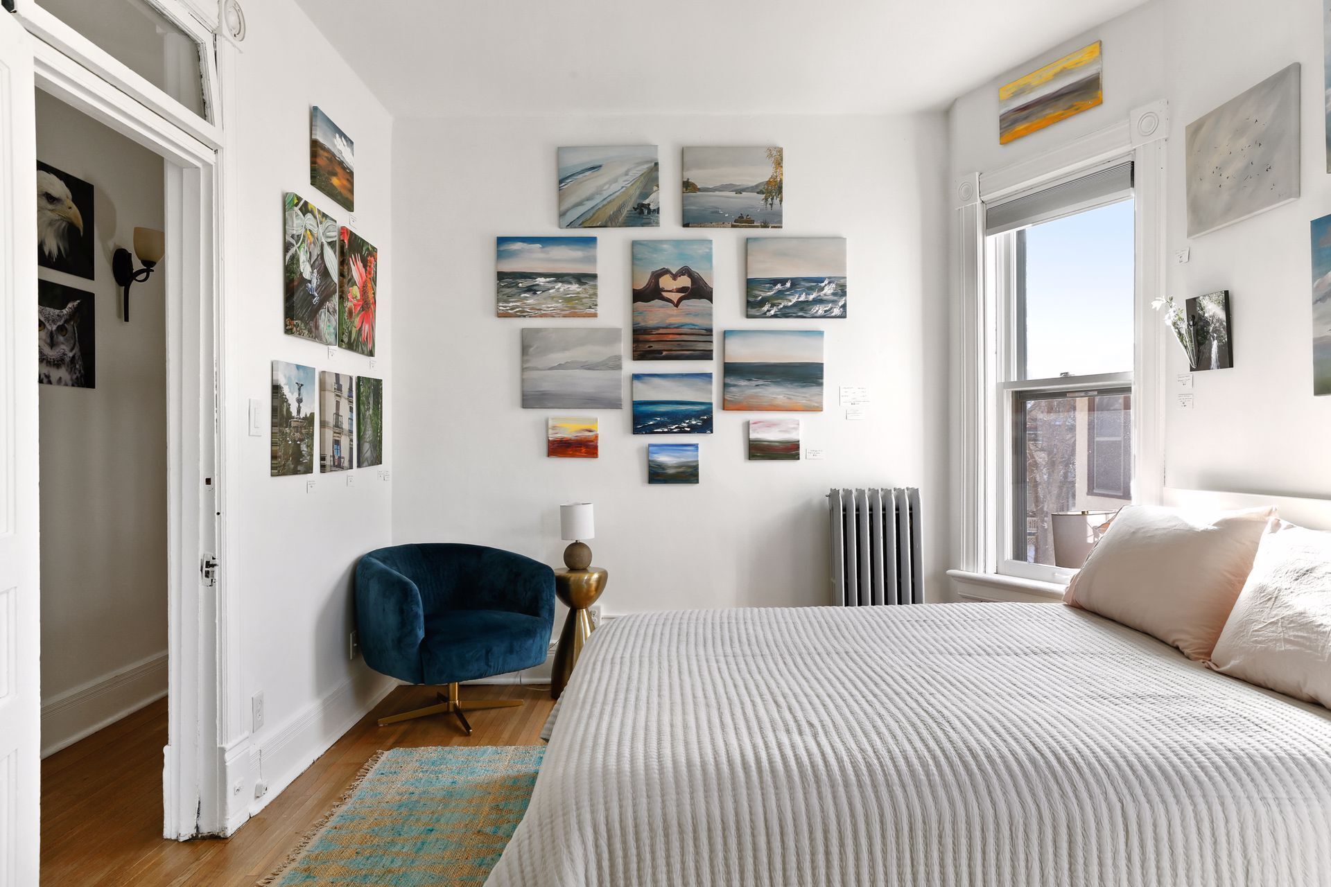 Une chambre à coucher avec un grand lit, une chaise bleue et un mur décoré de divers tableaux.