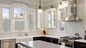 A modern kitchen with white cabinetry, a stainless steel range, and a large island with seating.