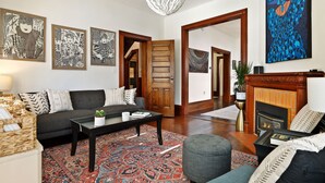 A living room with a sofa, coffee table, patterned rug, and artwork on the walls.