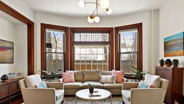 A cozy living room with a sectional sofa, a coffee table, and large windows with a view of a snowy landscape.