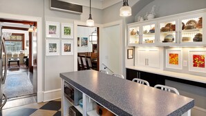 A modern kitchen with a granite countertop, white cabinetry, and a dining area with chairs.
