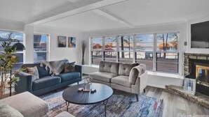 A spacious living room with a fireplace, large windows, and a view of a lake. - Perfect View of Cross Lake (Shreveport)