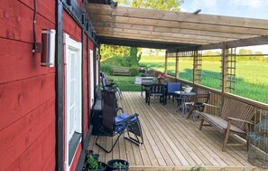 Relax on the covered deck with a variety of seating options and enjoy the view of the surrounding grassy field.