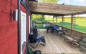 Relax on the covered deck with a variety of seating options and enjoy the view of the surrounding grassy field.