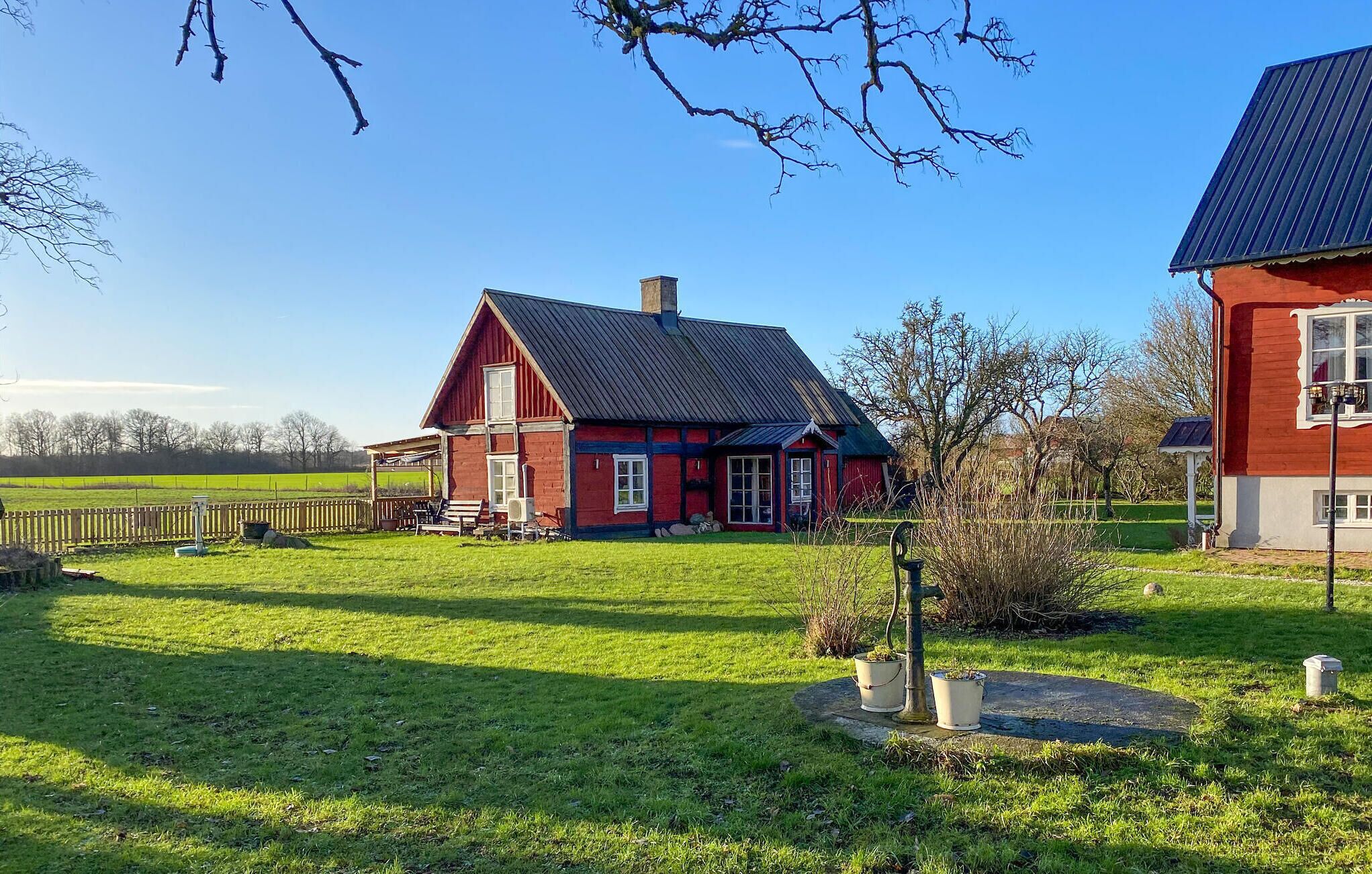 Ein rotes Haus mit Satteldach, einer Veranda und einem gepflegten Rasen.