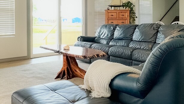 A living room with a leather sofa, a coffee table, and a wooden side table. There is a staircase in the background. - No Minimum Stay! No Chores! Kids allowed (Port O'Connor)