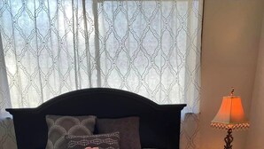 A neatly made bed with a tray of breakfast items, including tea, a bowl of fruit, and sugar cubes.