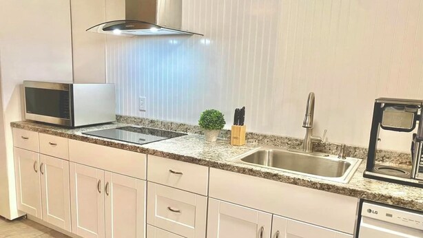 A modern kitchen with a built-in microwave, stainless steel sink, and an LG dishwasher.
