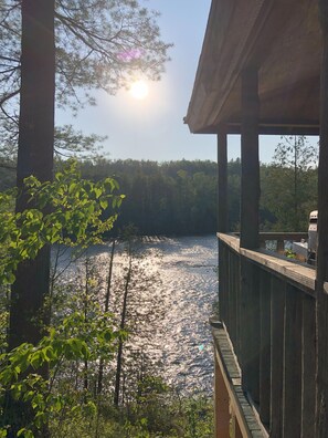 A wooden deck overlooking a lake with trees in the background. - Kennebec Riverside Cabins (West Forks)