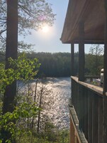A wooden deck overlooking a lake with trees in the background.