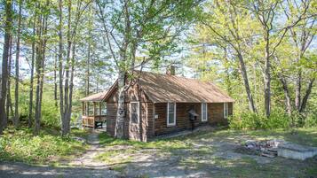 A rustic cabin with a wooden exterior, a porch, and a chimney.