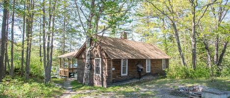 A rustic cabin with a wooden exterior, a porch, and a chimney.