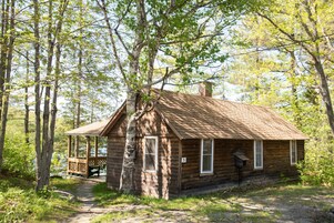 A rustic cabin with a wooden exterior, a porch, and a number '5' sign.
