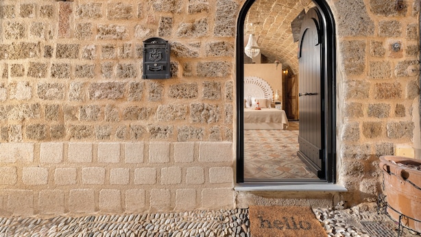 Un bâtiment en pierre avec une porte numérotée, un paillasson et un sol carrelé.