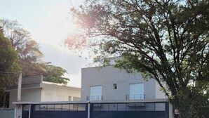 A modern building with a garage and a tree in front. - Pampering Suites (São Paulo)