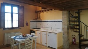 A kitchen with a wooden ceiling, a window with curtains, a sink, cabinets, and a table with chairs. - Aria Apartment: Romantic Stay with Breakfast (loc Resta Buonconvento)