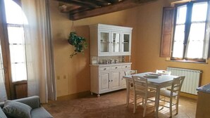 A cozy living room with a sofa and a dining area with a table and chairs. - Aria Apartment: Romantic Stay with Breakfast (loc Resta Buonconvento)