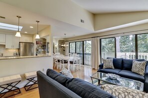 A spacious living area with a large window, a dark blue sofa, and a glass coffee table.