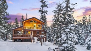 Una baita di legno con un balcone, circondata da alberi innevati.