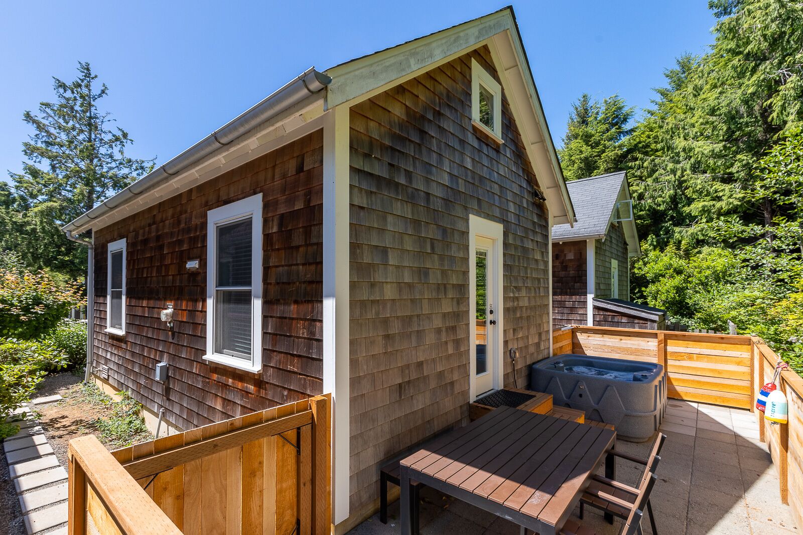A small wooden cabin with a hot tub and a table outside.