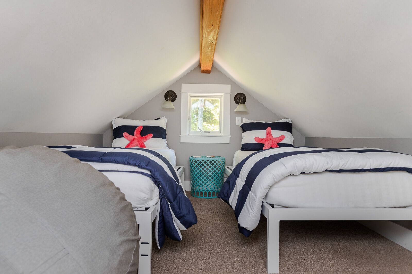 Une chambre avec deux lits, une fenêtre et un plafond avec une poutre en bois.