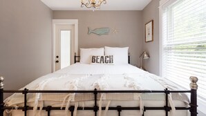 Een slaapkamer met een bed, een kroonluchter, decoratie van vissen en zeesterren, en een raam met jaloezieën.