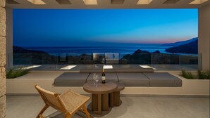 A modern outdoor seating area with a view of the ocean at dusk. - Villa 7 Seas - With Amazing View (Lefkogia)